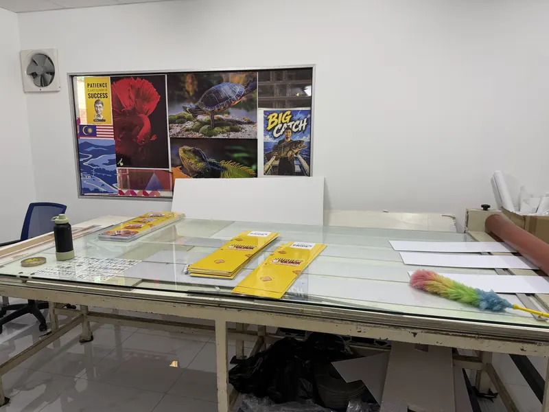 Boards on the finishing table, with print samples on the wall behind.